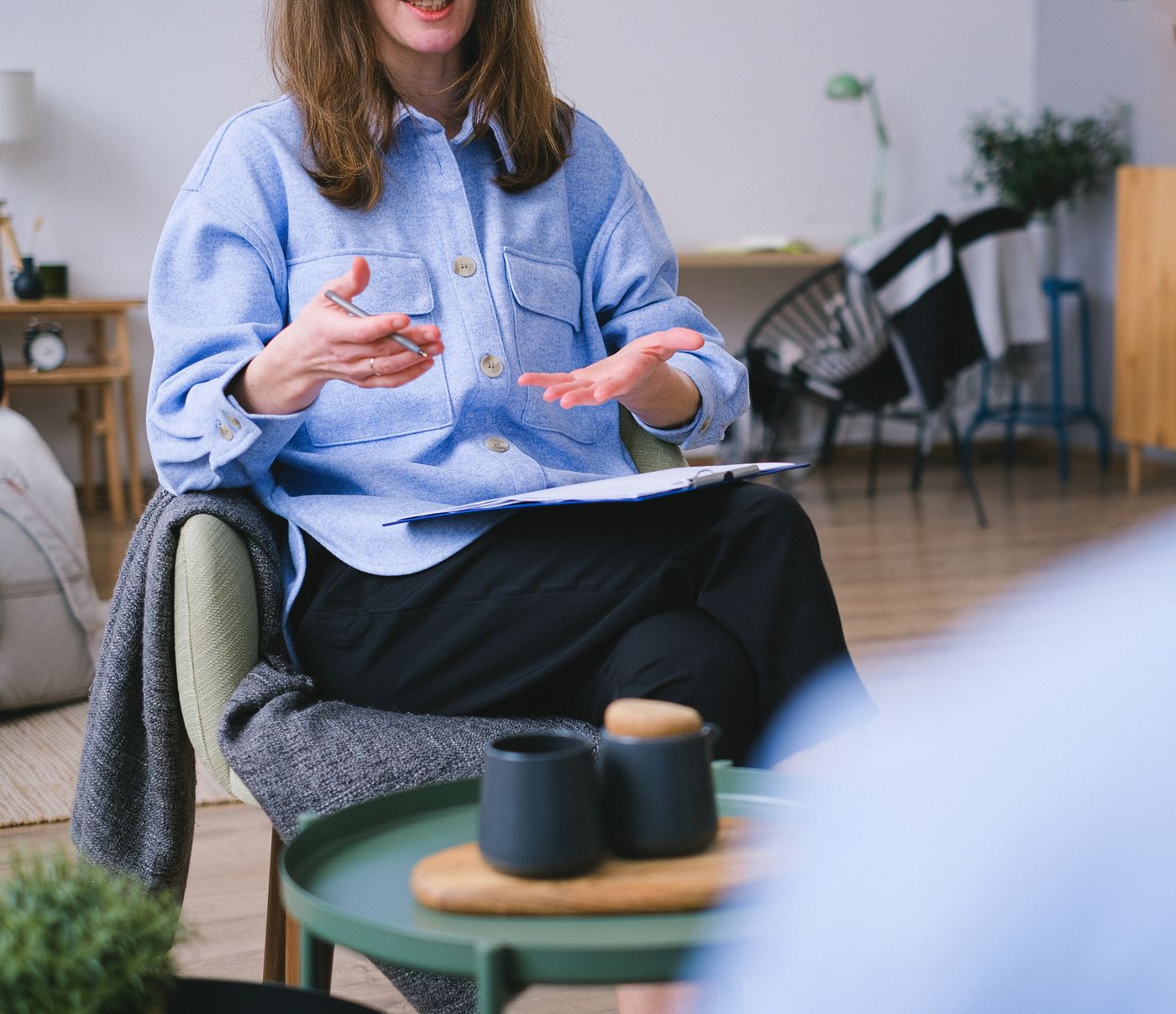 Een therapeute in gesprek, met open handen, aan het begin van een sessie